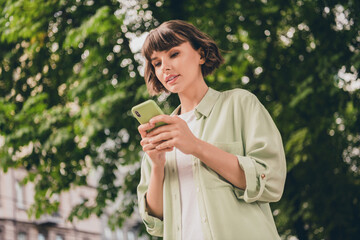 Low angle view portrait of attractive focused brown-haired girl using device gadget smm spending...