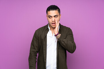 Asian handsome man isolated on blue background whispering something with surprise gesture while looking to the side