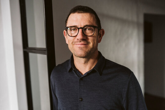 Portrait of smiling male professional leaning on doorway - Powered by Adobe