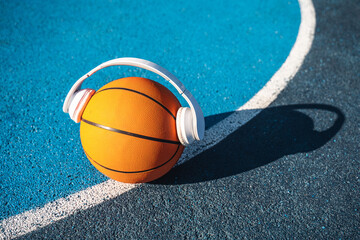 Basketball ball in wireless headphones standing at the stadium ground during the sunny day