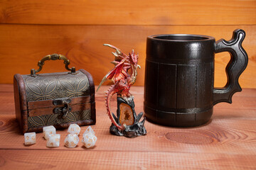 Set of role playing white dices,  wooden storage box, toy miniature of dragon and stylized beer mug...