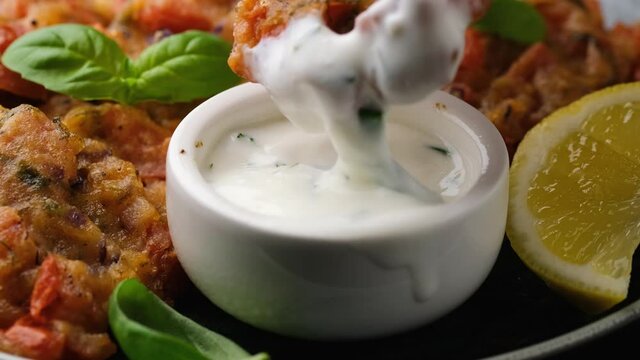 Dipping Greek tomato fritters, tomatokeftedes in yogurt