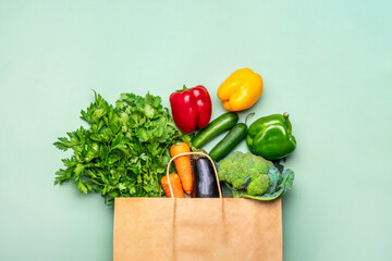 Eco friendly paper shop bag with raw organic green vegetables isolated on green background Flat lay, top view Zero waste, plastic free concept