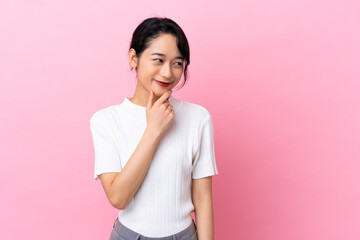 Fototapeta premium Young Vietnamese woman isolated on pink background looking to the side and smiling