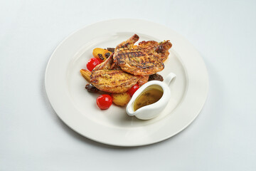 Grilled baked chicken with vegetables and sauce in a white plate on a white tablecloth. Coq au vin