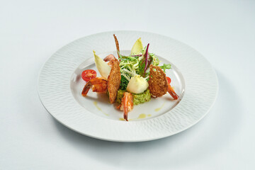 Mexican avocado guacamole in a white plate with shrimps and croutons.
