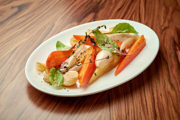 Roasted roots in wine sauce on a white plate on a wooden background