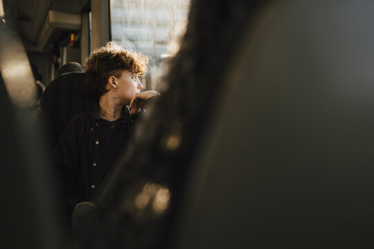 Teenage boy looking through window from bus