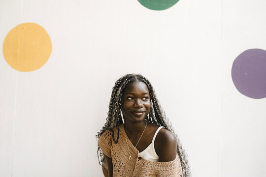 Smiling young woman against white wall with polka dots
