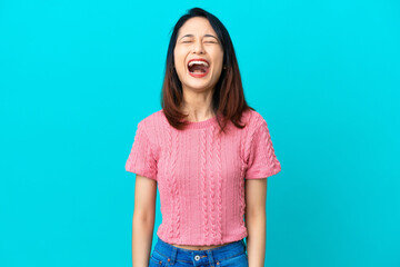Young Vietnamese woman isolated on blue background shouting to the front with mouth wide open