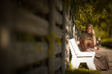 Fototapeta na wymiar Girl in folk costume sitting on a bench in Konstantinovo