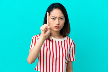 Fototapeta premium Young Vietnamese woman isolated on blue background counting one with serious expression