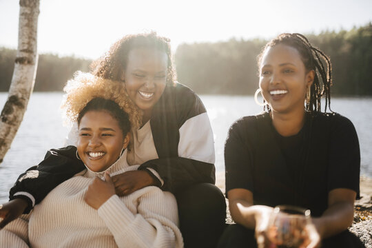 Cheerful female friends spending leisure time at lakeshore