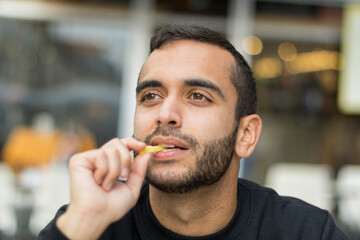 Primer plano de hombre jóven comiendo patatas fritas con diferentges y divertidas caras