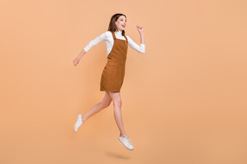 Fototapeta na wymiar Full body profile photo of carefree charming girl running look empty space isolated on beige color background