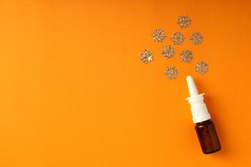 Blank bottle of nasal spray and decorative snowflakes on orange background