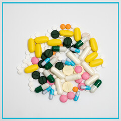 Variety of medicines and capsules in a woman's palm on a blue background. The concept of consuming a large number of drugs