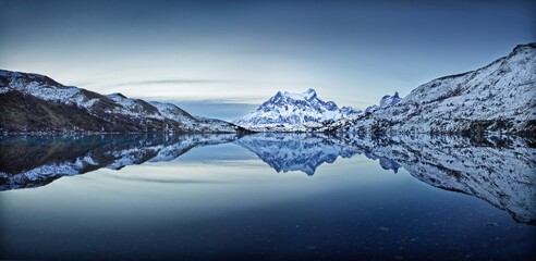 Winter in Patagonia: snow covered hills and mountains reflect in the Serrano river in Torres del...