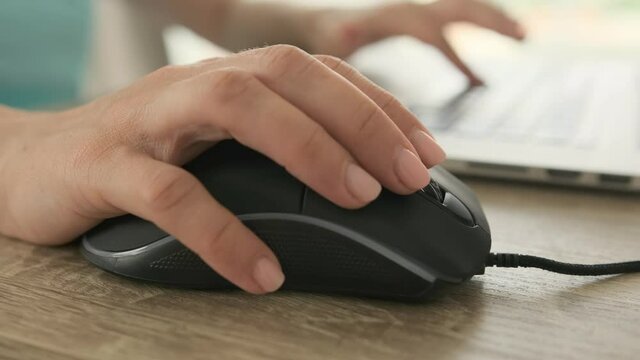 Hands using mouse and typing on laptop keyboard. Closeup view of person working with keypad