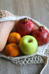 Crochet bag filled with butternut squash, pomegranates, apples and tangeriens. Selective focus.