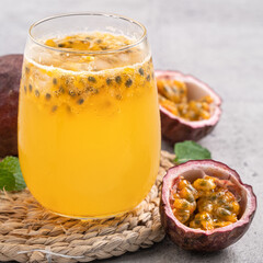 Delicious juicy passion fruit with sparkling juice on gray table background.