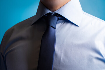 A man in a blue shirt and blue tie. Close-up of the chest of an office employee against a blue background.