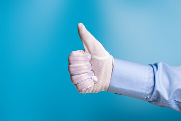 A man's hand in a white fabric anti-static anti-slip glove shows like on a blue background.