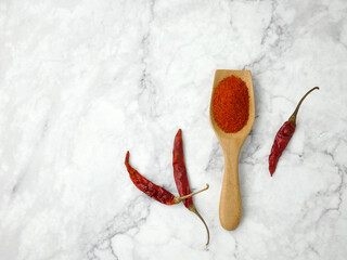 Chili powder and dried chilli in spoon on marble background, cayenne pepper.