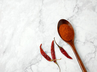 Chili powder and dried chilli in spoon on marble background, cayenne pepper.