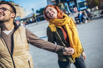 Smiling couple enjoying on vacation, young tourist having fun walking and exploring city street during the day.