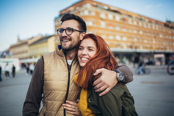 Smiling couple enjoying on vacation, young tourist having fun walking and exploring city street during the day. - obrazy, fototapety, plakaty