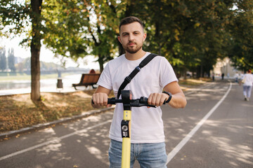 Young man riding an electric scooter on a meeting. Ecological transportation concept. Handsome man outdoors with e-scooter