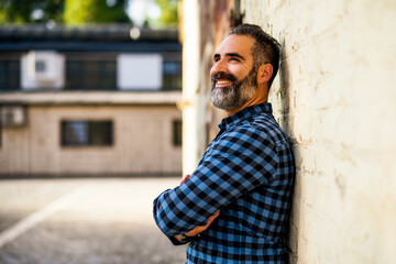 Portrait of modern businessman with beard standing in front of  wall outdoor.	