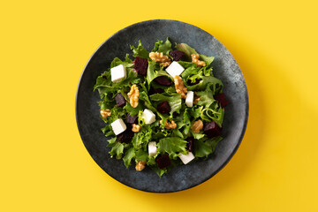 Beetroot salad with feta cheese,lettuce and walnuts on yellow background