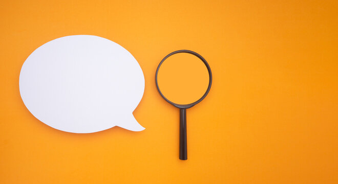 Top view of a blank white speech bubble and a magnifying glass isolated on a yellow background. Space for text