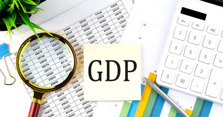 GDP text on sticker on diagram with magnifier and calculator. Business concept