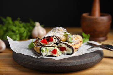 Delicious baked eggplant rolls served on wooden table