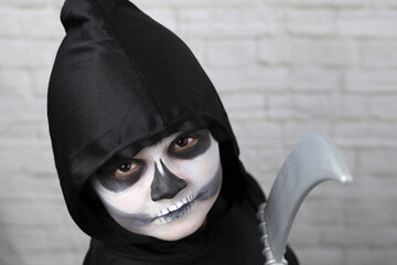 niño con disfraz de muerte, con capucha guadaña y maquillaje - 468158822