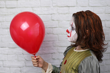 niño con disfraz de payaso malvado con la cara y el pelo pintados