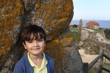 niño feliz posando cerca de la playa - 468158869
