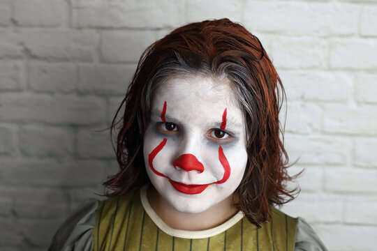 ni&ntilde;o con disfraz de payaso malvado con la cara y el pelo pintados