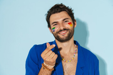 Shirtless man with rainbow flag rubbing his fingers and smiling