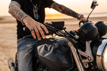 Mature man wearing black t-shirt with tattoo posing on motorbike