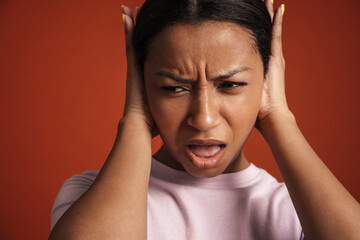 Young african american woman frowning and covering her ears