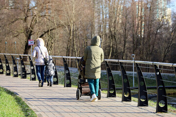 Woman walking with baby pram in autumn park. Mothers with children, leisure on nature