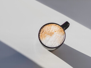 Top view on cup of cappuccino. Geometrical minimalist background with coffee mug. Light, shadow and...
