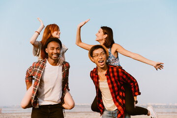 Young multiracial couples giving high five and piggybacking together