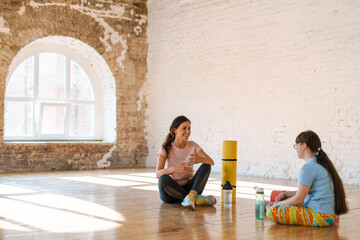 Young woman with down syndrome talking with her yoga coach indoors