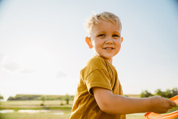 Blonde white boy laughing while playing with frisbee