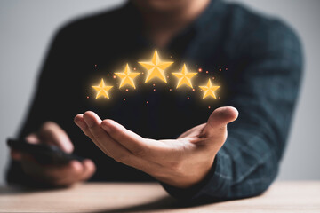 Businessman holding golden five stars for client customer feedback and evaluation after use service and product concept.